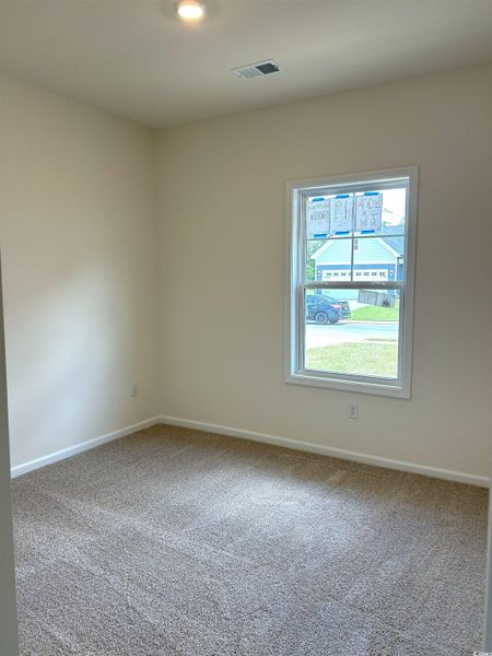 Carpeted spare room featuring baseboards