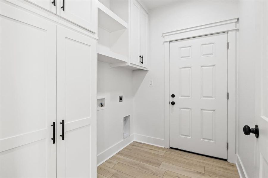 Laundry area with light wood-type flooring, cabinet space, electric dryer hookup, and washer hookup