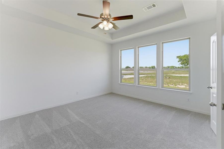 Spacious room featuring three large windows, light gray carpeting, and a white ceiling fan with integrated lighting