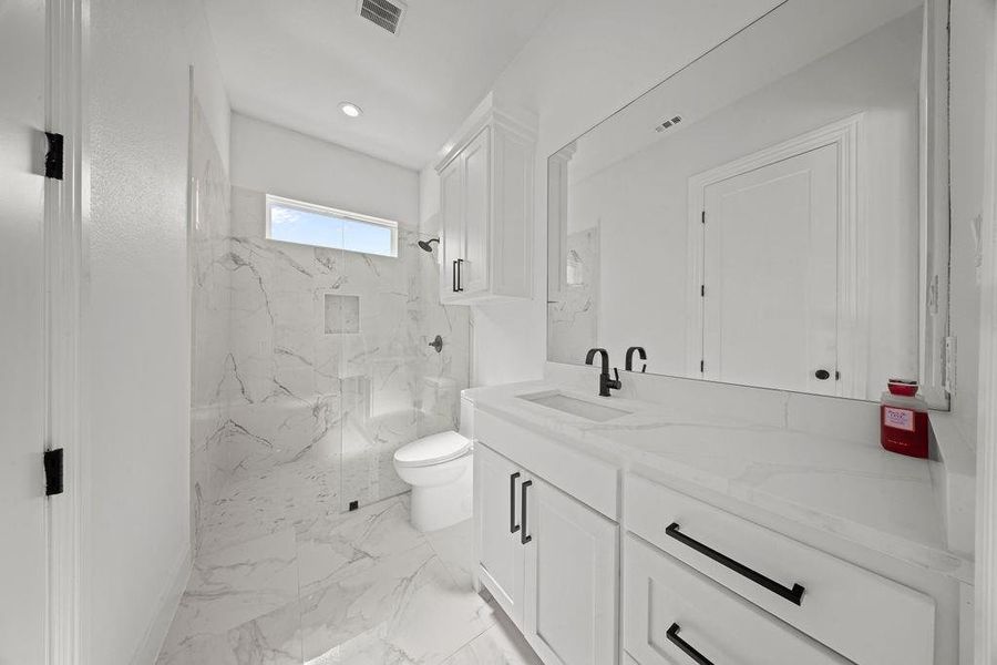 Bathroom with vanity, a marble finish shower, recessed lighting, and light marble finish flooring