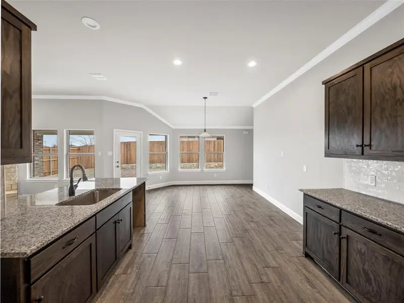 Kitchen featuring a wealth of natural light, baseboards, a sink, and dark brown cabinets Kitchen featuring a wealth of natural light, baseboards, a sink, and dark brown cabinets