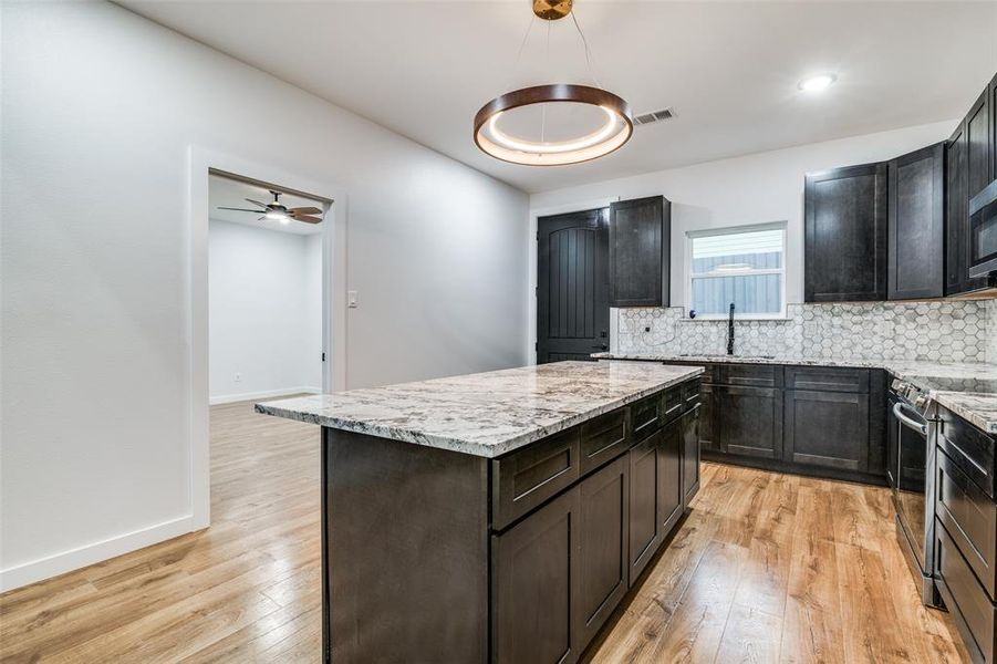 Kitchen with stainless steel range, light hardwood / wood-style flooring, sink, and a kitchen island