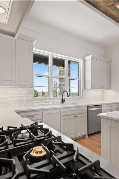 Kitchen featuring decorative backsplash, gas cooktop, ornamental molding, dishwasher, and light wood-style floors Kitchen featuring decorative backsplash, gas cooktop, ornamental molding, dishwasher, and light wood-style floors