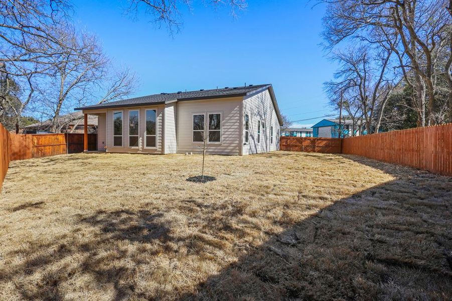 Back of property featuring a lawn and a fenced backyard