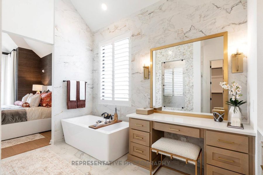 Full bath featuring a freestanding bath, healthy amount of natural light, vaulted ceiling, vanity, and marble finish flooring Full bath featuring a freestanding bath, healthy amount of natural light, vaulted ceiling, vanity, and marble finish flooring