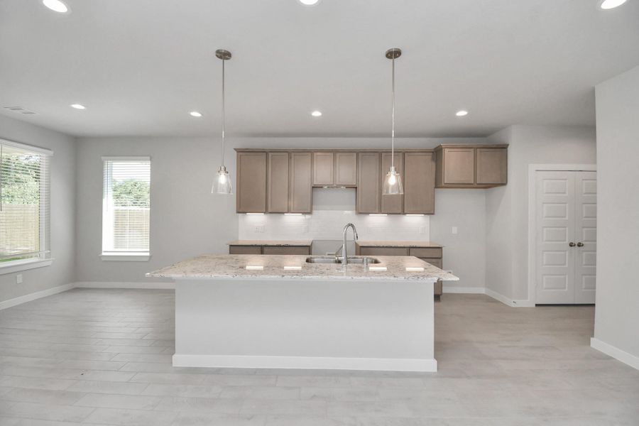 The kitchen is a culinary haven, featuring granite countertops, a tile backsplash, stainless steel appliances, 42” upper cabinets, and undercabinet lighting. Sample photo of completed home with similar floor plan. Actual colors and selections may vary. The kitchen is a culinary haven, featuring granite countertops, a tile backsplash, stainless steel appliances, 42” upper cabinets, and undercabinet lighting. Sample photo of completed home with similar floor plan. Actual colors and selections may vary.
