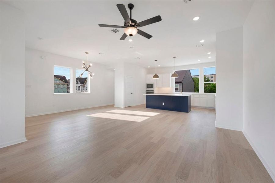 Open-concept living space featuring light wood-finish flooring, white walls, and recessed lighting