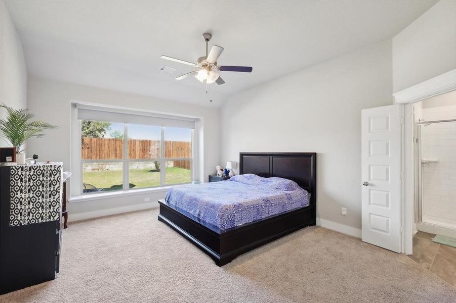 Bedroom featuring ceiling fan, light colored carpet, and ensuite bathroom