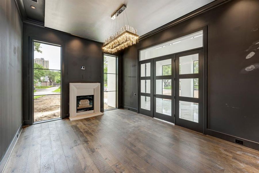 Refined study adjacent to the foyer, boasting soaring floor-to-ceiling windows, timeless fireplace, and a captivating chandelier. Stage of construction as of June 4, 2025. Refined study adjacent to the foyer, boasting soaring floor-to-ceiling windows, timeless fireplace, and a captivating chandelier. Stage of construction as of June 4, 2025.