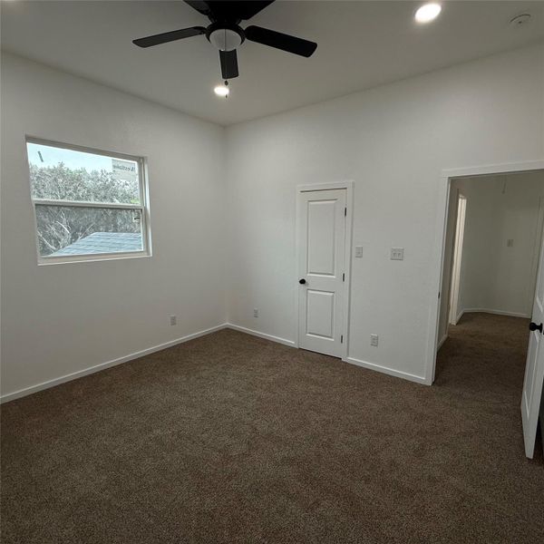 Spacious room featuring neutral carpeting, a dual-pane window, and a contemporary ceiling fan with integrated lighting