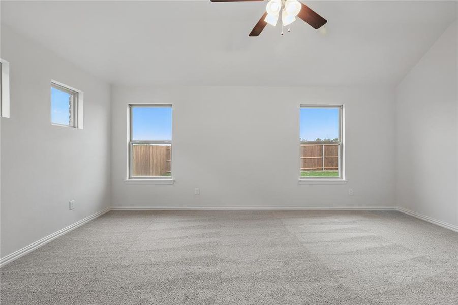 Unfurnished room with a ceiling fan, light carpet, and plenty of natural light