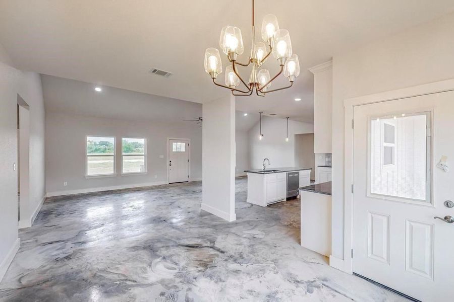 Unfurnished living room featuring sink, lofted ceiling, and ceiling fan with notable chandelier