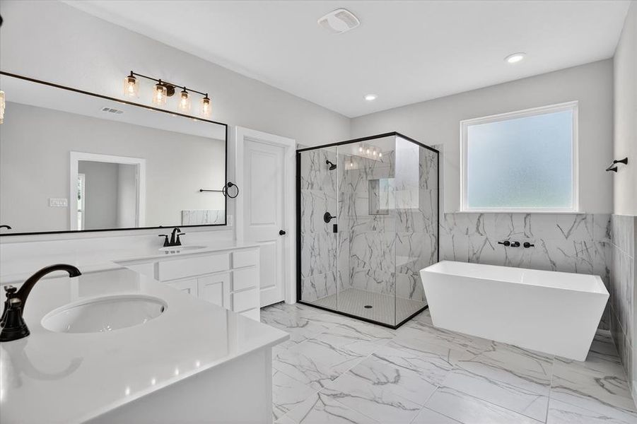 Spacious bathroom featuring a freestanding soaking tub, a frameless glass shower enclosure, and dual vanities with white countertops