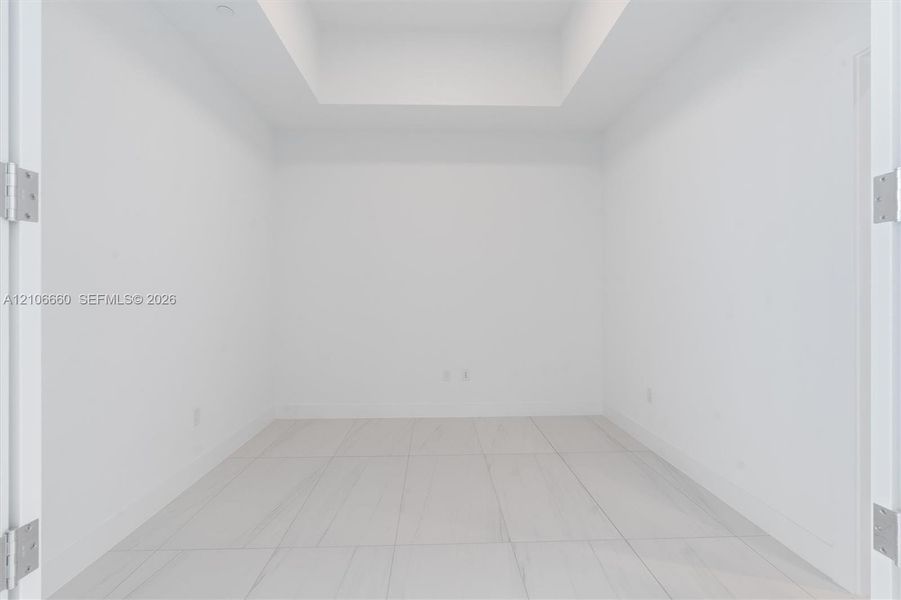 Interior space featuring a recessed ceiling, white walls, and large-format tile flooring