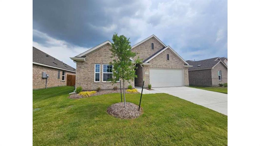 Single-story residence featuring a light brick exterior with white trim, an attached garage, and a concrete driveway