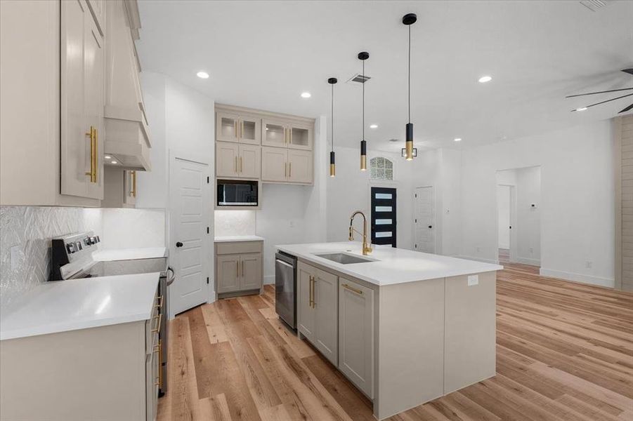 Kitchen featuring sink, light hardwood / wood-style floors, a center island with sink, and appliances with stainless steel finishes