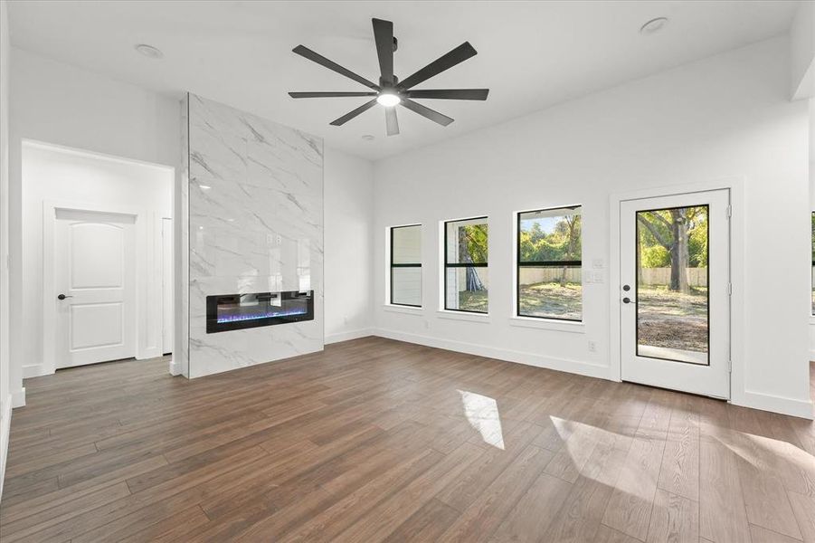 Unfurnished living room with a fireplace, ceiling fan, and dark hardwood / wood-style flooring