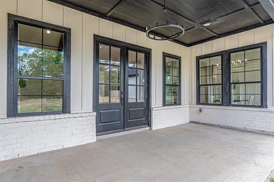 Covered patio featuring a concrete surface, white brick accents, and vertical wood siding