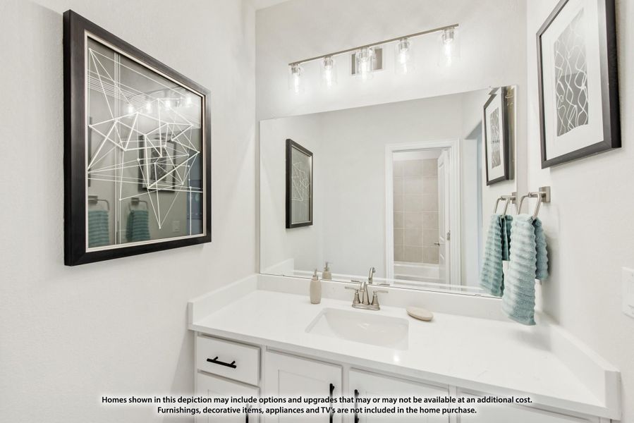 Bathroom vanity with white cabinets, quartz countertop, large mirror, and brushed nickel light fixture above sink