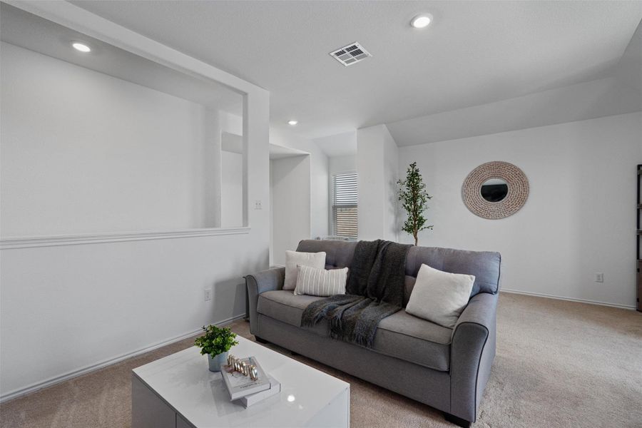 Living area with light carpet and recessed lighting