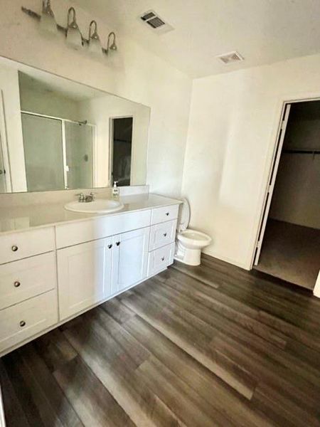 Bathroom featuring vanity, walk in shower, toilet, and hardwood / wood-style floors