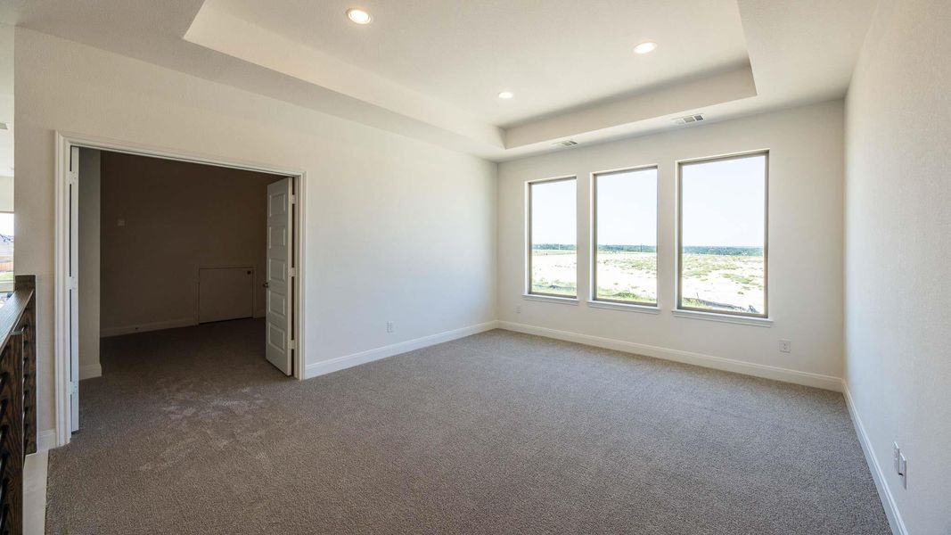 Unfurnished bedroom with a raised ceiling, light colored carpet, and recessed lighting Unfurnished bedroom with a raised ceiling, light colored carpet, and recessed lighting