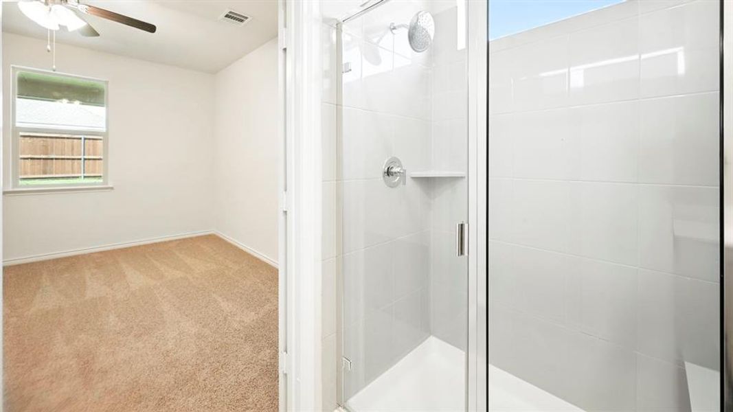 Bathroom featuring carpet flooring, a shower stall, and a ceiling fan
