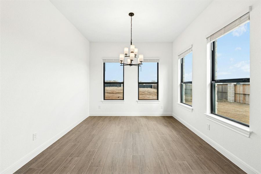 Unfurnished dining area with dark wood-type flooring, suspended lighting, and plenty of natural light