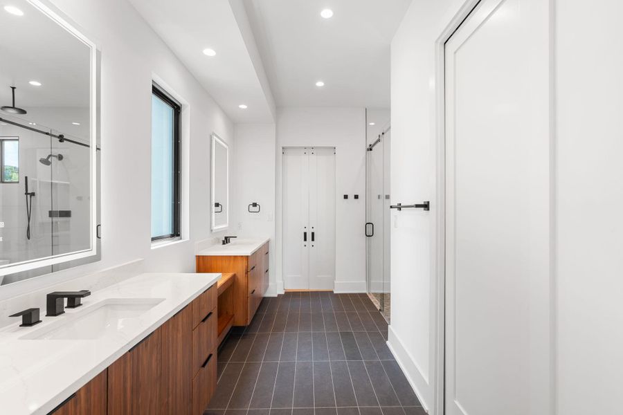 Dual vanities with sleek countertops and rich wood cabinetry define this well-appointed bath.