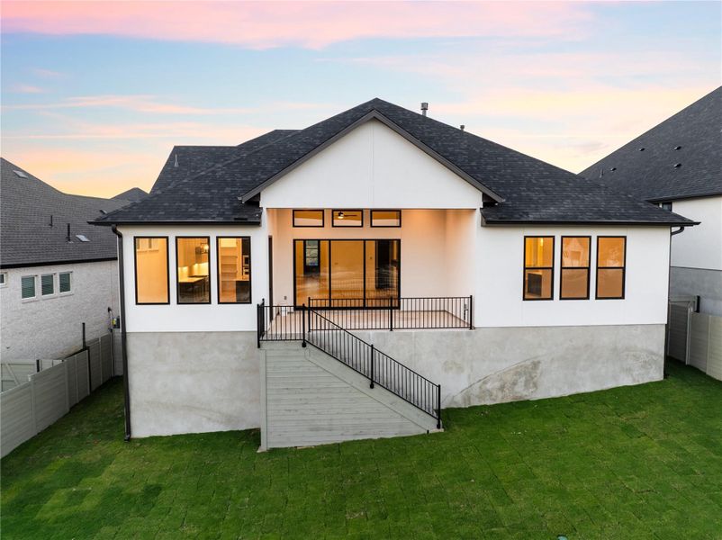 Rear view of house featuring roof with shingles and stucco siding