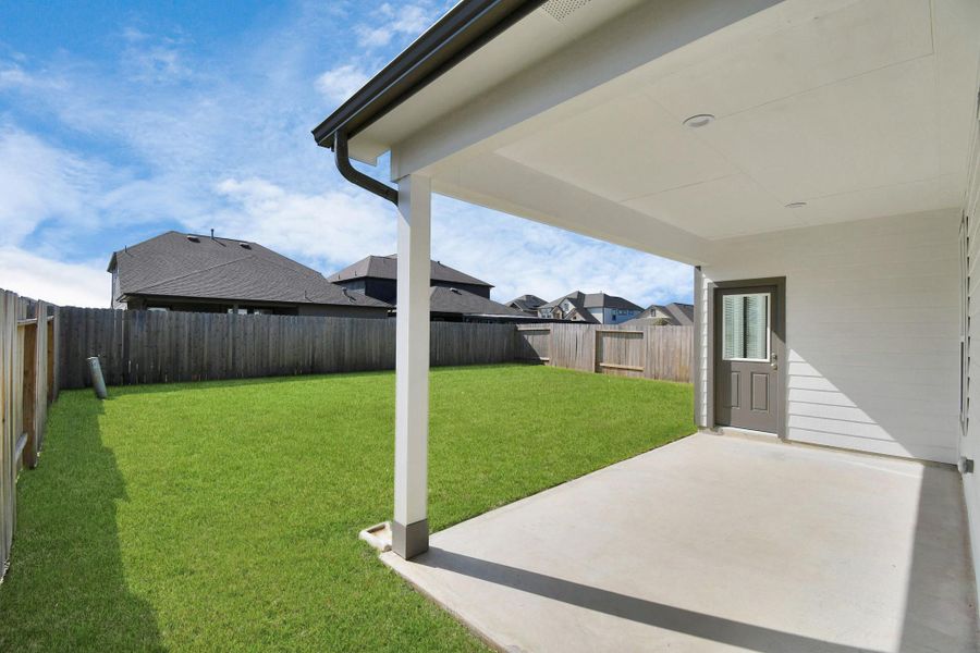 Experience outdoor living at its finest on this expansive covered patio, thoughtfully designed for BBQs and delightful outdoor dining. Sample photo of completed home with similar floor plan. Actual colors and selections may vary.
