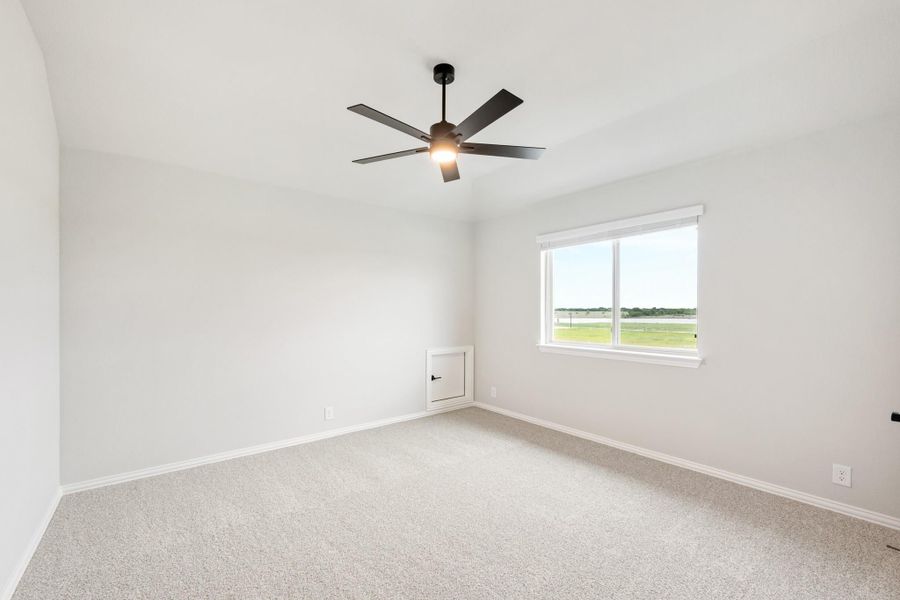 Empty bedroom with light carpet, black ceiling fan, and a window with outdoor views