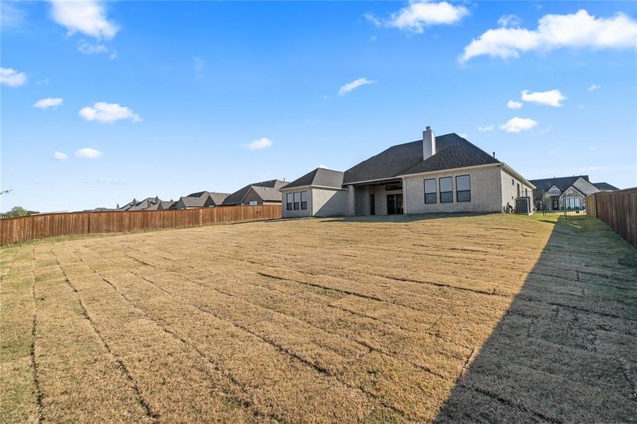 Back of house with a fenced backyard, brick siding, a patio, a chimney, and a residential view Back of house with a fenced backyard, brick siding, a patio, a chimney, and a residential view