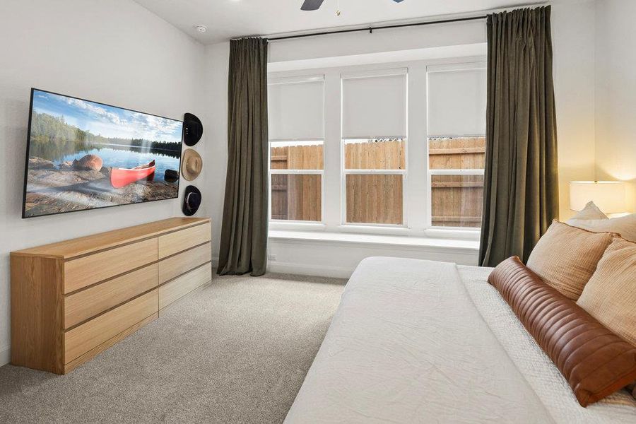 Carpeted bedroom with multiple windows and ceiling fan