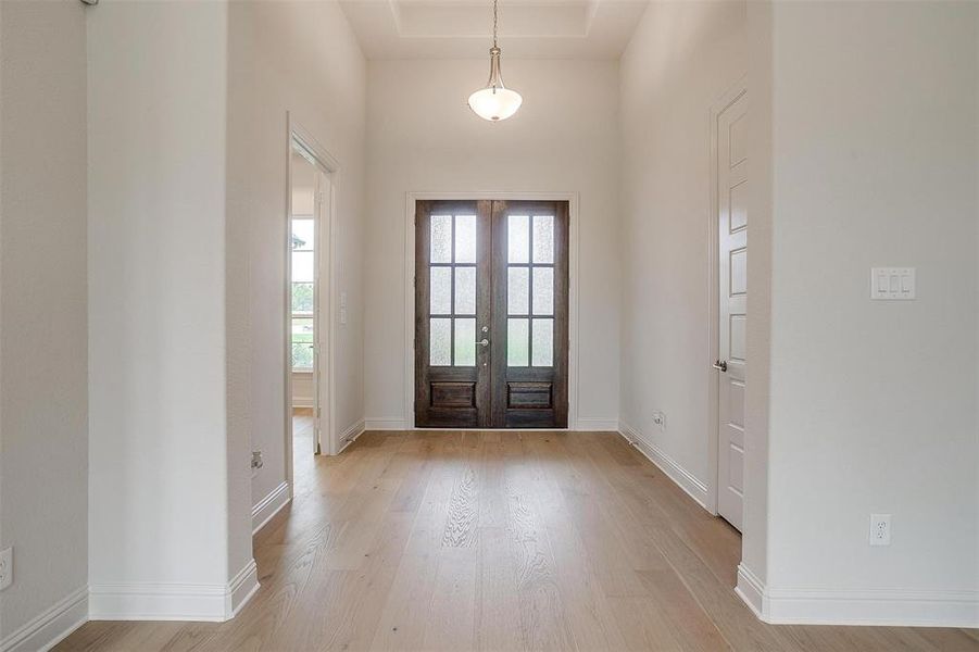 Foyer entrance with light wood-type flooring and french doors