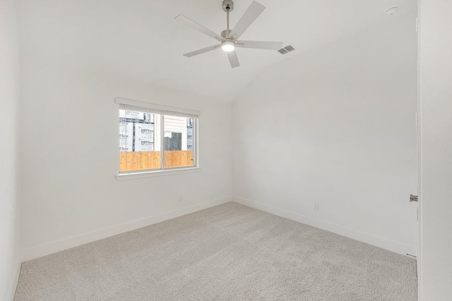 Empty bedroom with vaulted ceiling, ceiling fan, carpet flooring, and single window Empty bedroom with vaulted ceiling, ceiling fan, carpet flooring, and single window