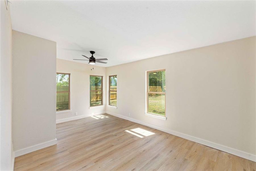 Empty room featuring light wood finished floors, plenty of natural light, and a ceiling fan Empty room featuring light wood finished floors, plenty of natural light, and a ceiling fan