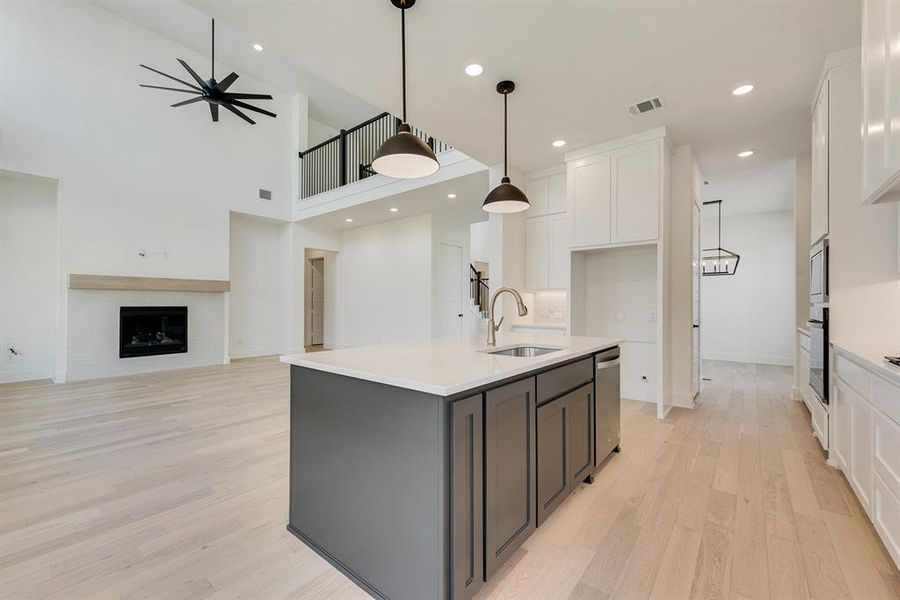 Kitchen with white cabinets, light wood-style floors, an island with sink, open floor plan, and recessed lighting