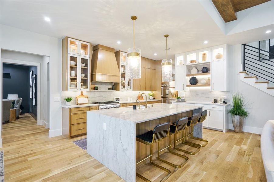 Kitchen with white oak cabinetry, quartzite counter tops, custom range hood