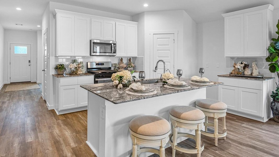 Kitchen adorned with white cabinets seamlessly integrated into an open dining area layout.