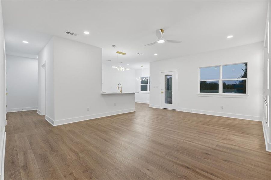 Spacious open-concept living area featuring wood-finish flooring, recessed lighting, and a modern ceiling fan