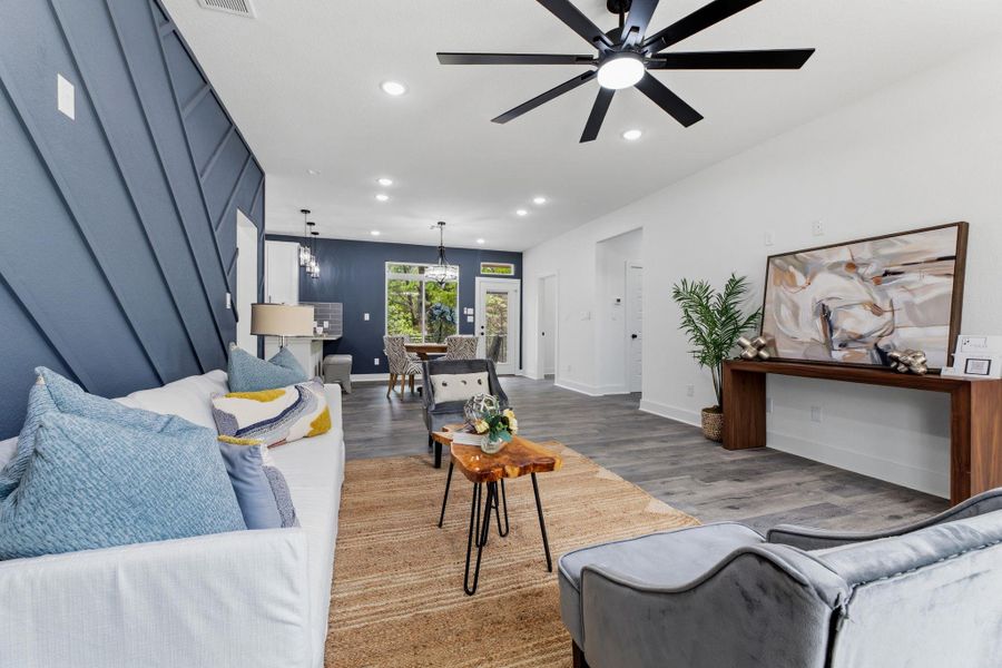 An open-concept living space with sleek flooring connects to a dining area with views of nature.