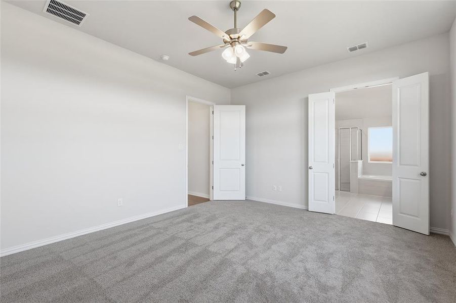 Unfurnished bedroom with carpet flooring, ceiling fan, and connected bathroom Unfurnished bedroom with carpet flooring, ceiling fan, and connected bathroom