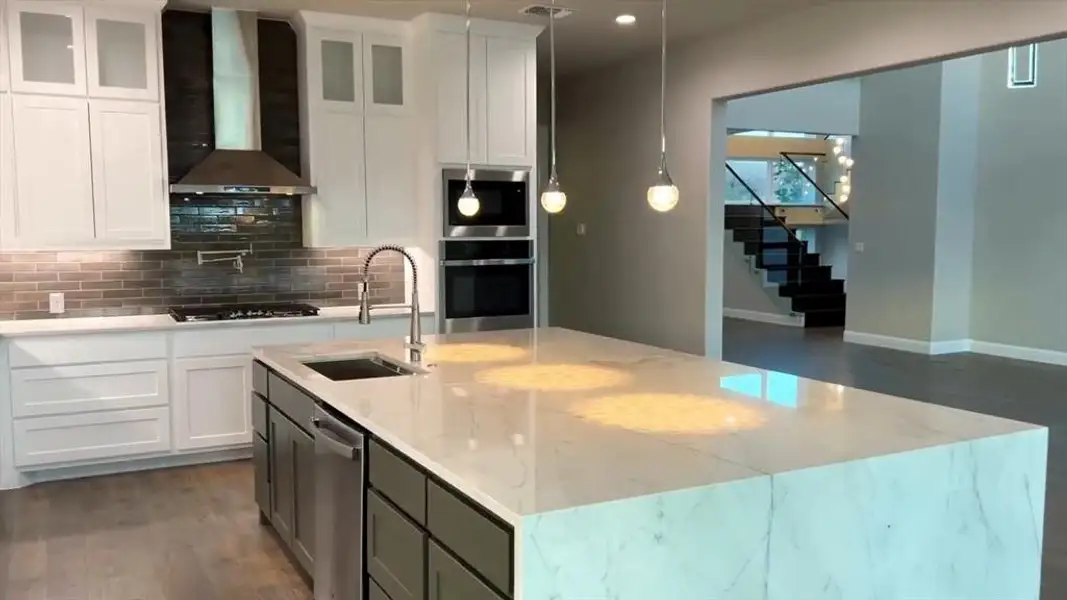 Kitchen with white cabinets, wall chimney exhaust hood, light stone counters, tasteful backsplash, and appliances with stainless steel finishes