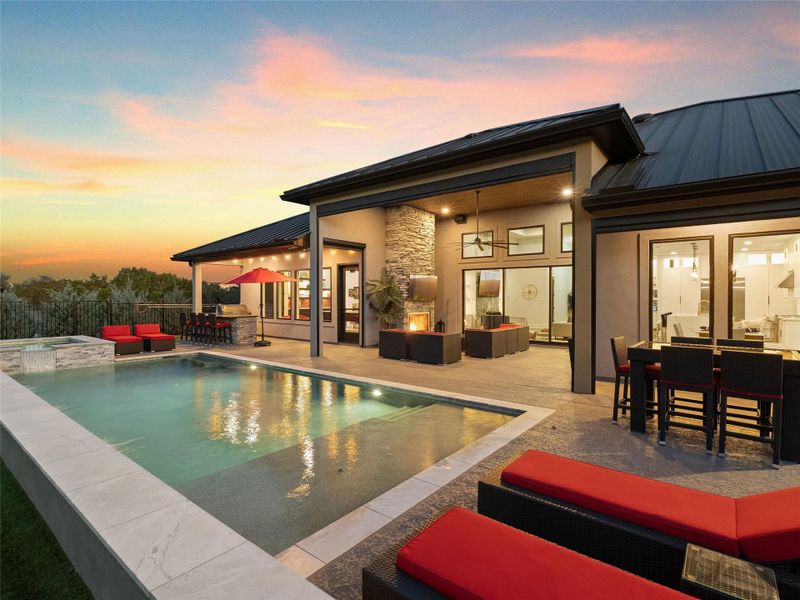 Back of house featuring an outdoor fire pit, a standing seam roof, a patio, and a pool with connected hot tub