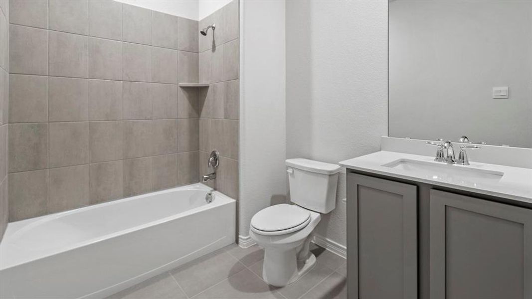Full bathroom featuring vanity, bathing tub / shower combination, light tile patterned floors, and a textured wall