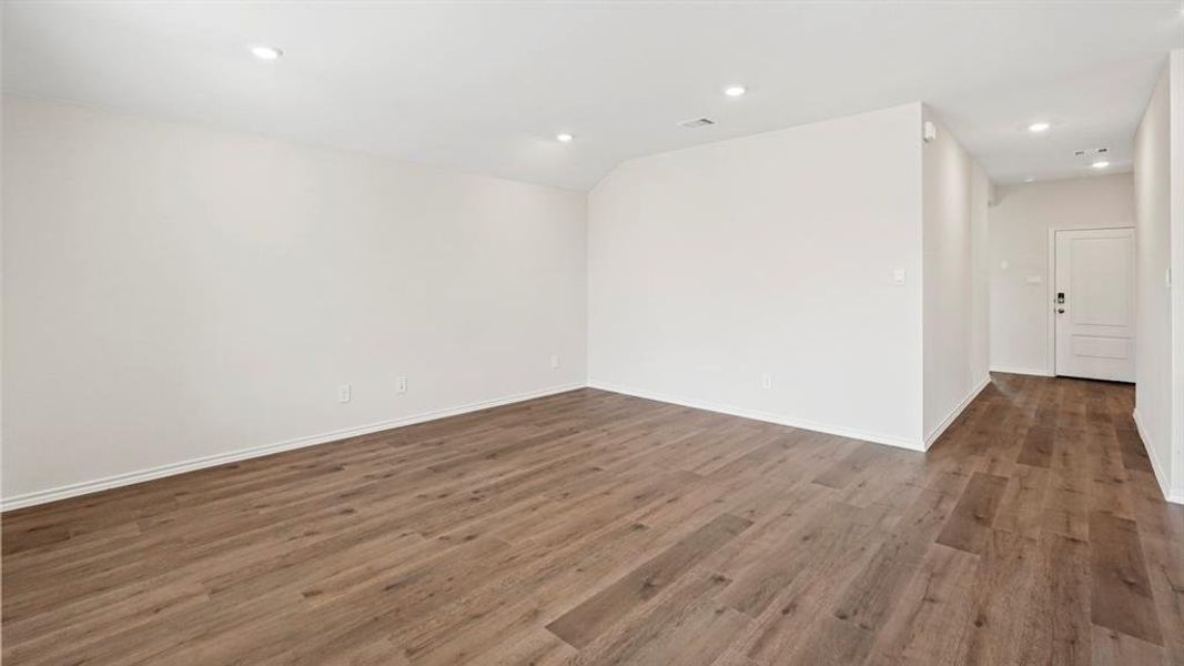 Spacious interior featuring wood-finish flooring, recessed lighting, white baseboards, and a white paneled door