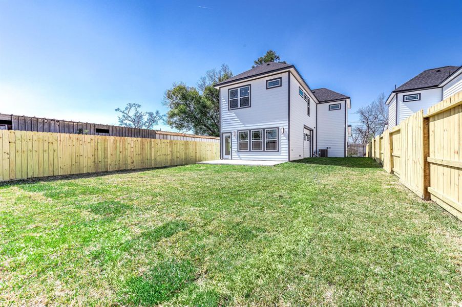Rear exterior view showcasing a spacious yard with fresh sod, a brand-new fence, and plenty of room to create your ideal outdoor retreat.