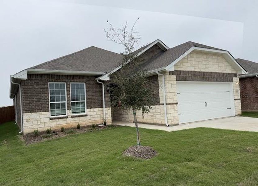 View of front facade with an attached garage, stone siding, a shingled roof, a front yard, and concrete driveway View of front facade with an attached garage, stone siding, a shingled roof, a front yard, and concrete driveway