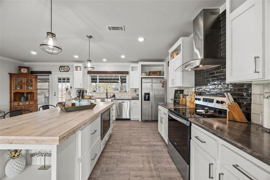 Kitchen featuring stainless steel appliances, glass fronted cabinets, white cabinetry, decorative backsplash, and crown molding